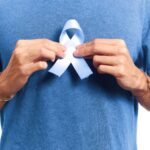 Mann hält blaues Band als Symbol für Männergesundheit und Vorsorge